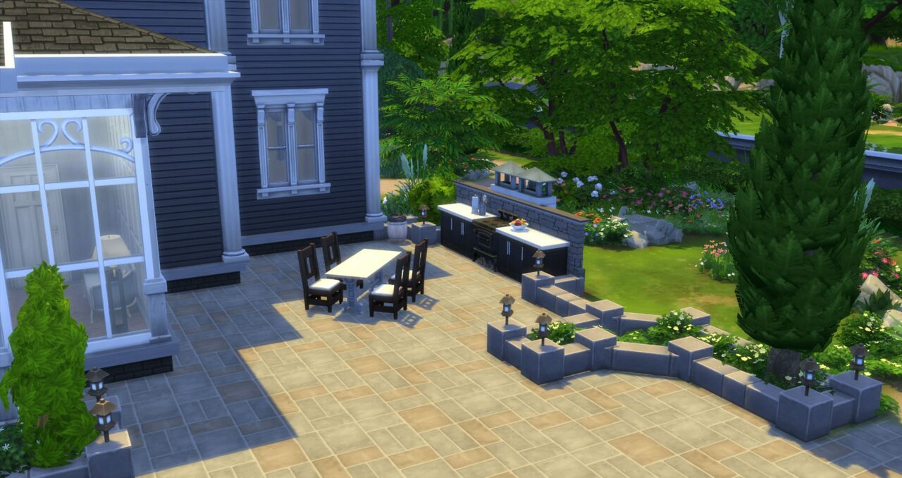 Une petite terrasse avec table, chaises et espace cuisine offre l’occasion aux Sims de manger dehors